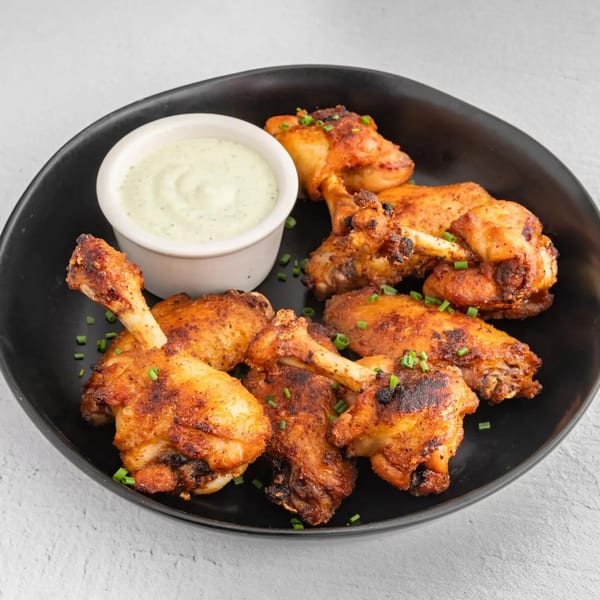 How Ya Dough'n Pizza's crispy chicken wings with green onions and a side of creamy dipping sauce.